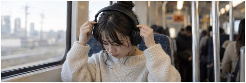 Woman adjusting over-ear headphones to fit a small head on a train